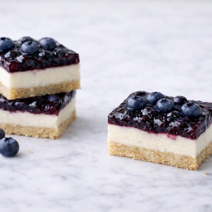 Blueberry cream cheese bars with shortbread crust and blueberry topping on marble surface