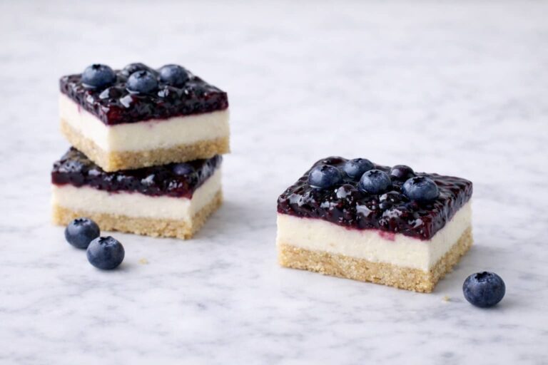 Blueberry cream cheese bars with shortbread crust and blueberry topping on marble surface
