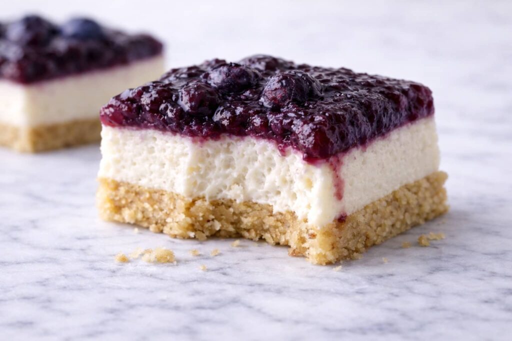 Close-up of blueberry cream cheese bars showing creamy filling, shortbread crust, and rustic blueberry topping