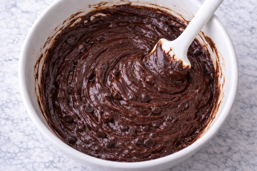 thick glossy brownie batter in mixing bowl with chocolate chips