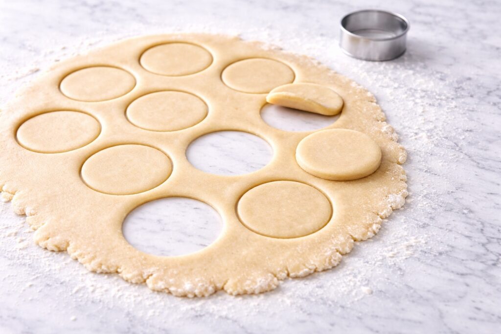 Rolled sugar cookie dough with round cutouts showing clean edges