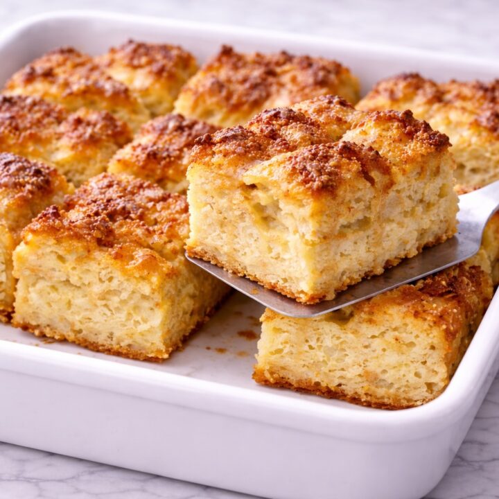 slice of baked french toast casserole lifted from the baking dish showing soft custardy texture