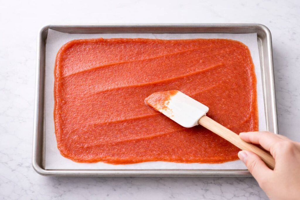 How to Spread Fruit Puree for Fruit Roll Ups spreading fruit puree evenly on baking sheet for homemade fruit roll ups