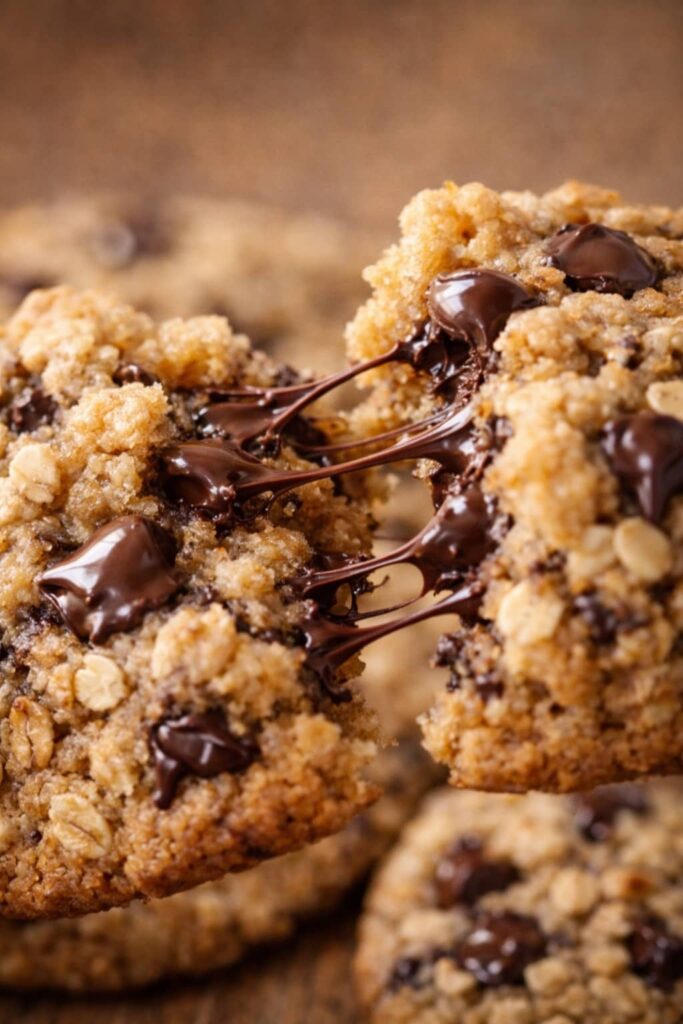 close up of chewy oatmeal chocolate chip cookies broken in half with melted chocolate chips