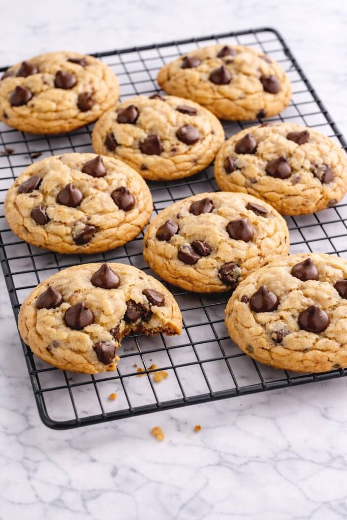 Freshly baked chocolate chip cookies cooling on wire rack with soft centers and crisp edges