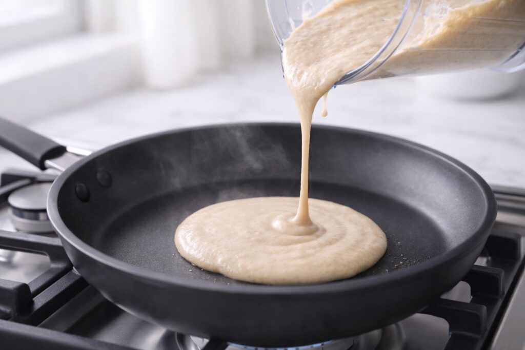 Protein pancake batter being poured into pan forming a round pancake