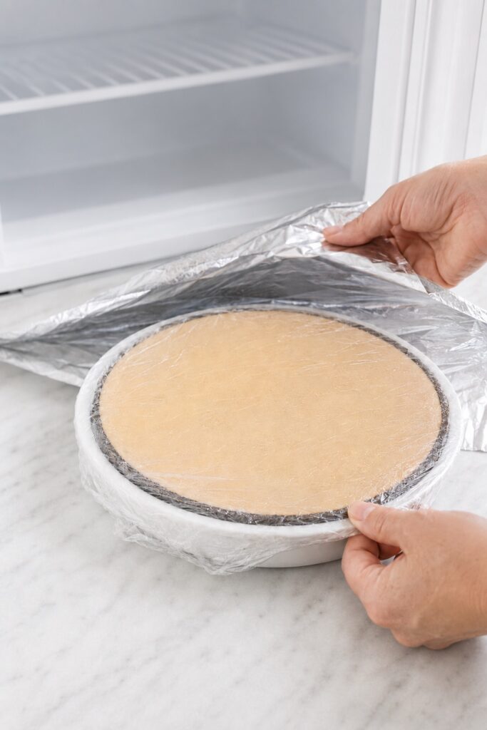 Untopped Peanut Butter Pie being tightly wrapped for freezer storage.