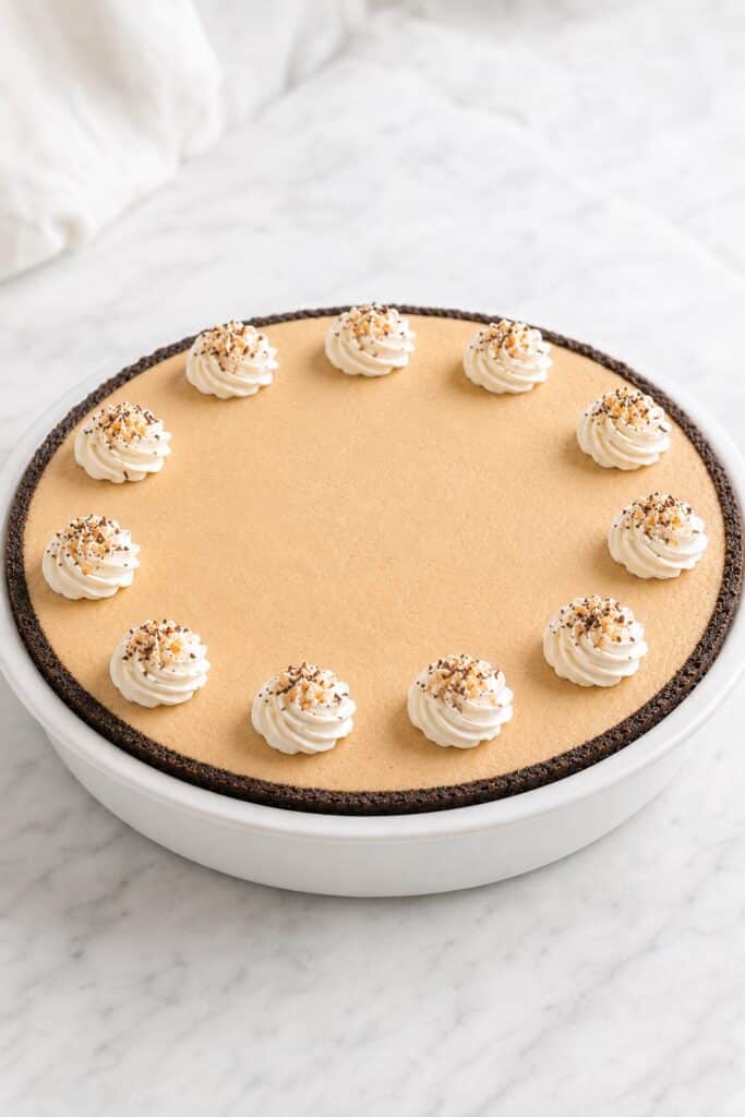 Finished Peanut Butter Pie topped with whipped cream swirls, chopped peanuts, and dark chocolate shavings.