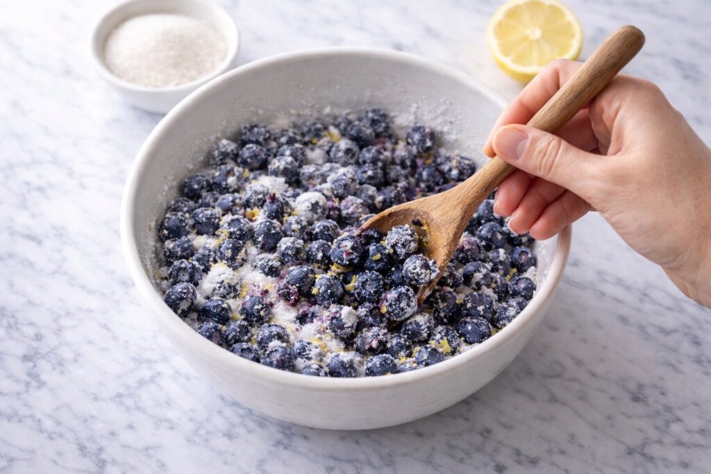 mixing blueberries sugar and cornstarch to prepare blueberry pie filling