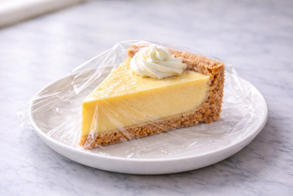 slice of key lime pie covered with plastic wrap for refrigerator storage