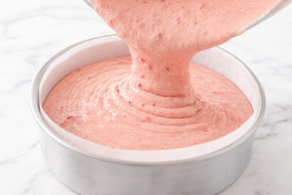 Pouring Strawberry Cake Batter into Pan strawberry cake batter being poured into round cake pan smooth pink batter
