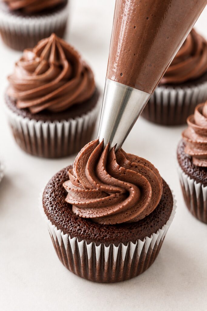 Pipping Frosting On Chocolate Cupcakes