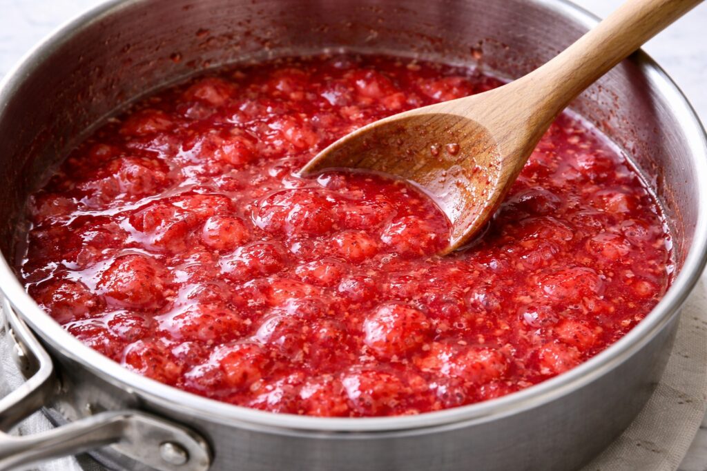 cooking strawberry pie glaze with mashed strawberries in saucepan