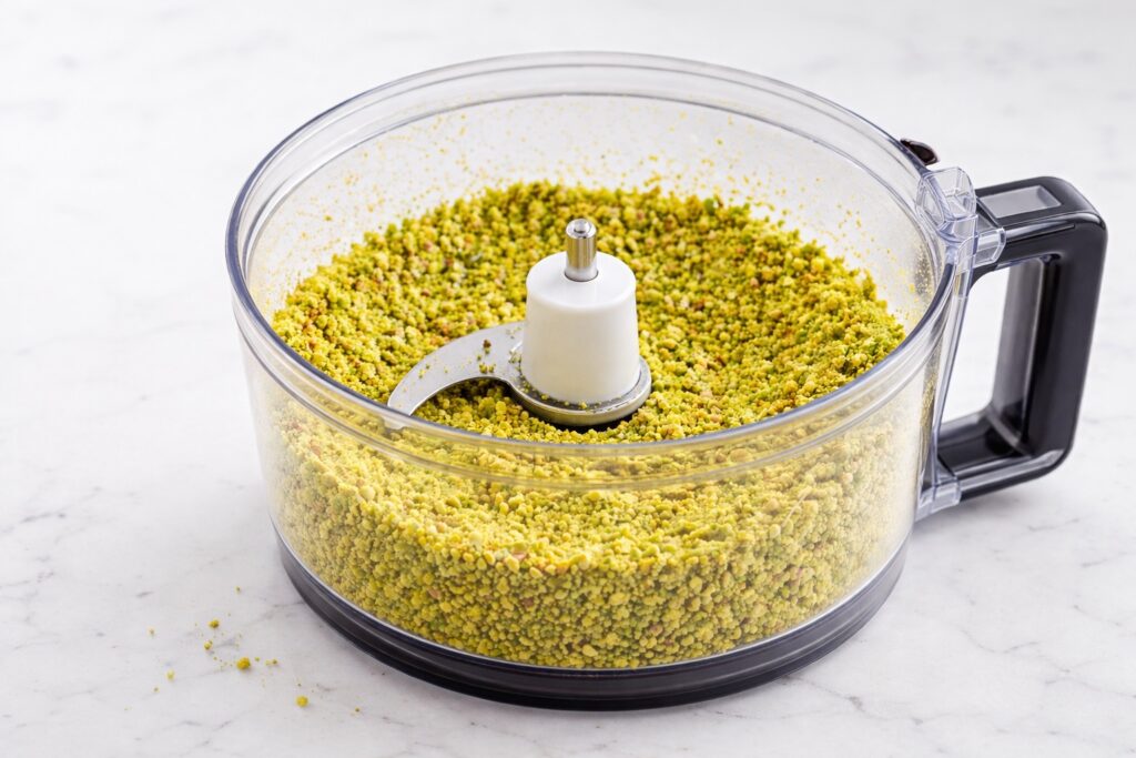Finely ground pistachios with a soft sandy texture in a food processor, ready for pistachio cake batter