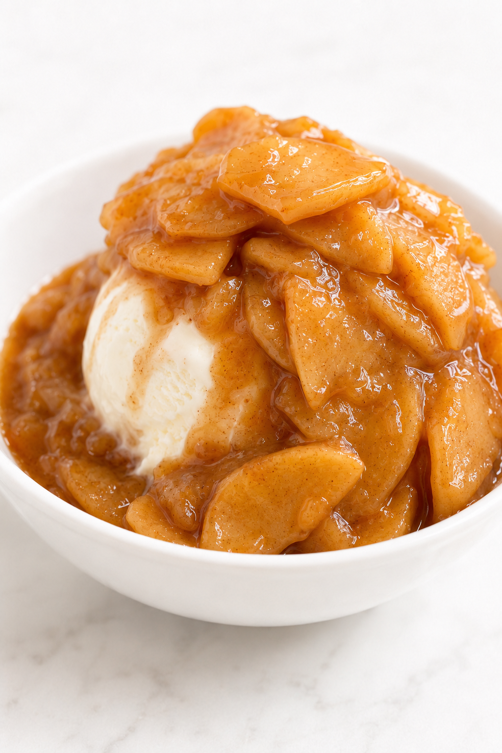 Warm homemade apple pie filling spooned over a restrained scoop of vanilla ice cream.