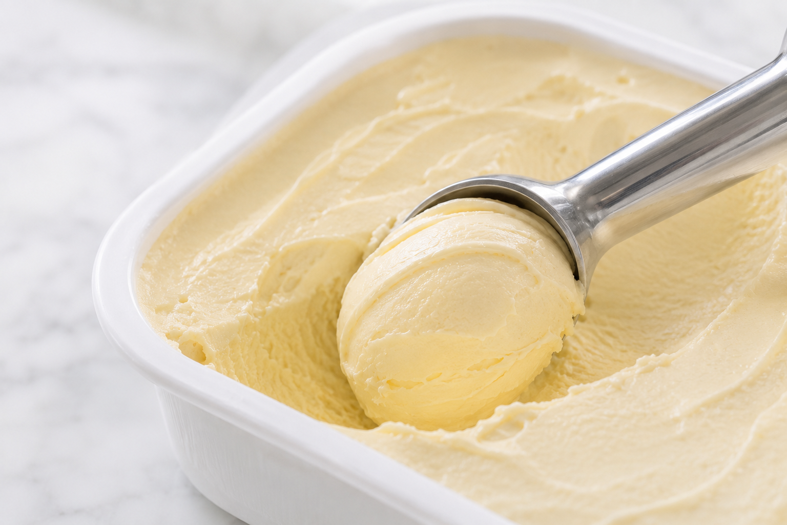 A scoop passing through tempered gelato to form compact rounded folds