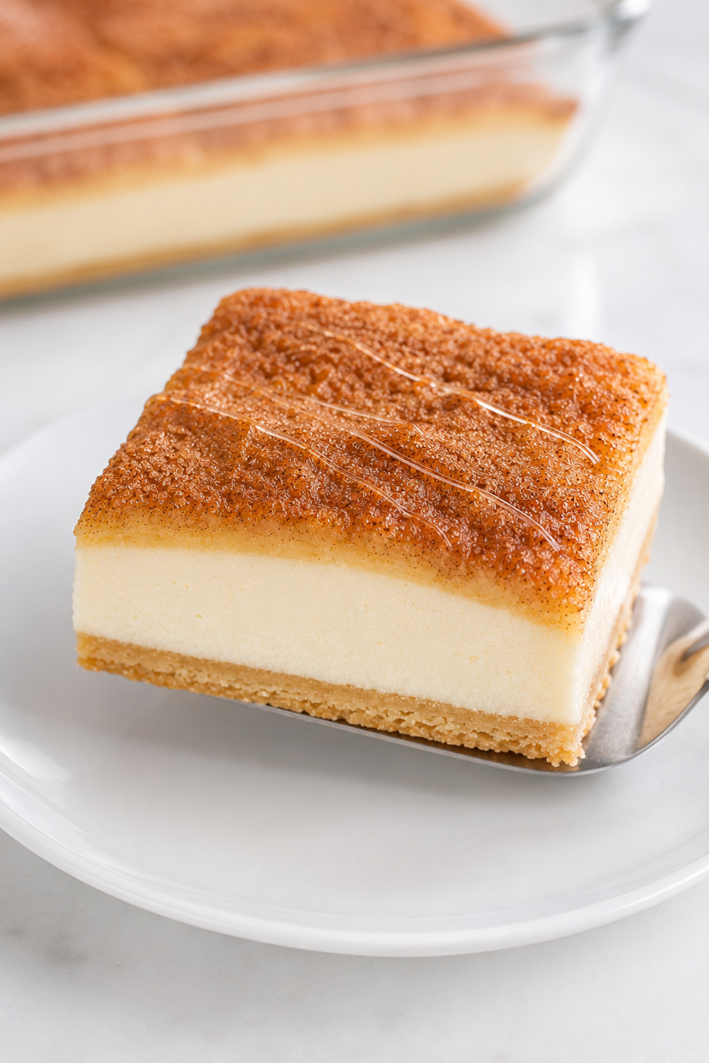 Chilled Sopapilla Cheesecake bar with clean pastry and cheesecake layers finished with fine honey threads.