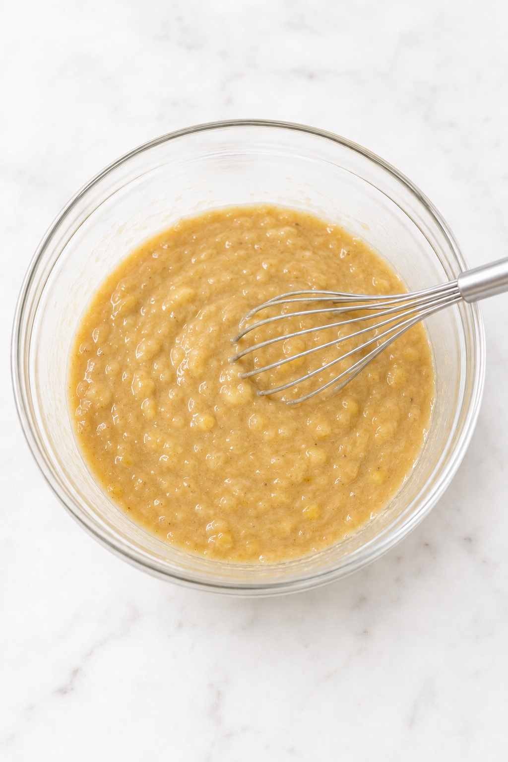 Glossy banana muffin wet mixture after the butter, sugars, egg, and vanilla are combined.
