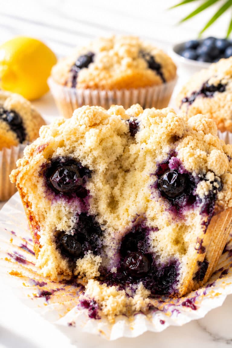 Lemon blueberry muffin broken open to show pale lemon crumb, baked blueberries, and streusel