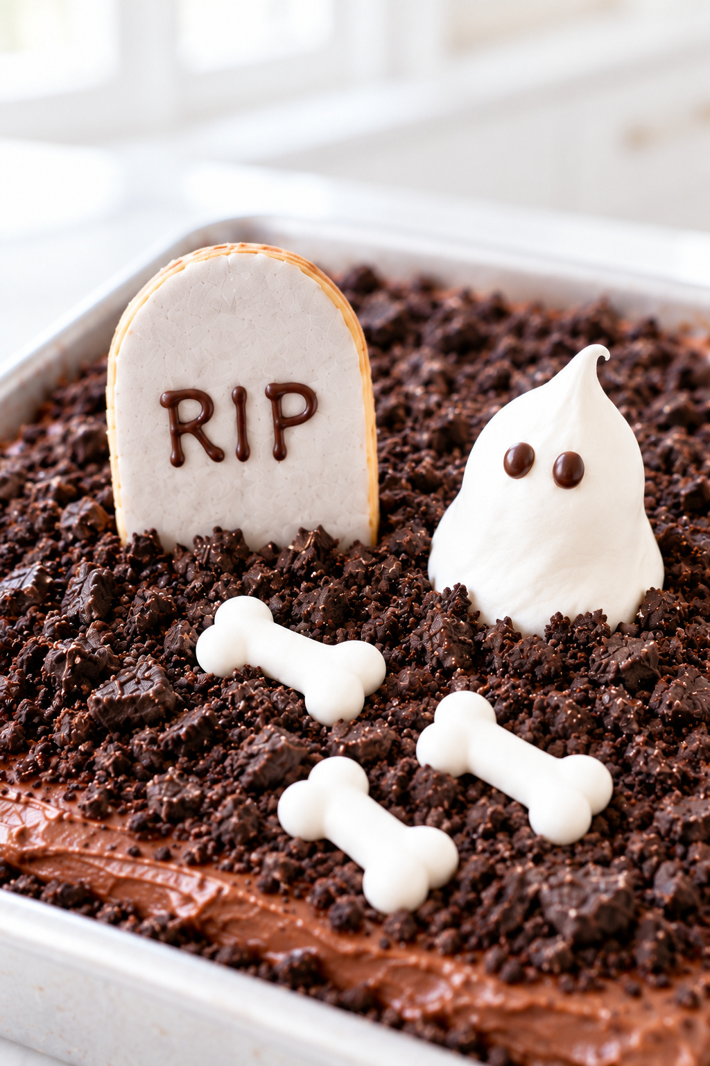 Close-up of gray tombstones, white ghosts, pumpkins, gummy worms, and bones on Oreo soil